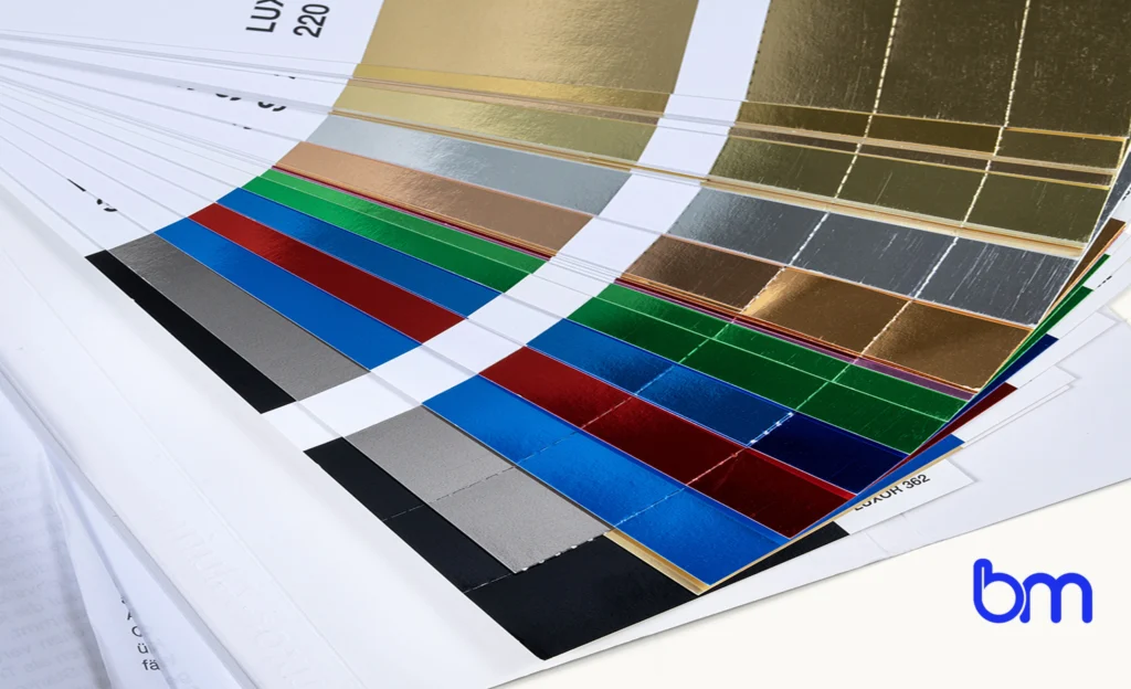 Stalenwaaier met luxe foliedruk in goud, zilver, rood, blauw, groen en zwart, voorbeeld van premium boekafwerking met Boekenmakers-logo rechtsonder.