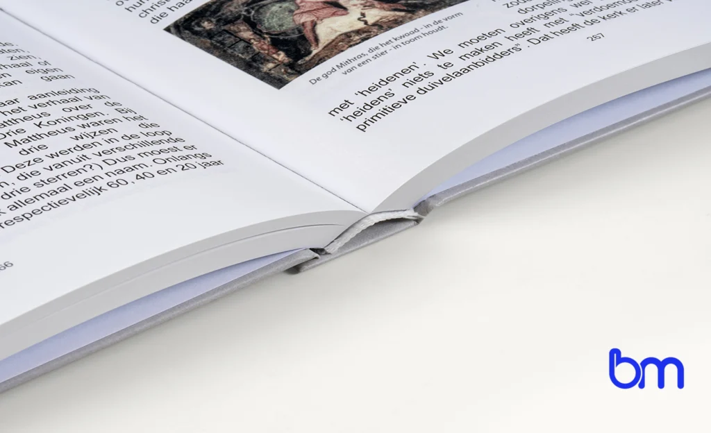 Open hardcoverboek met zichtbare rug en tekst op de pagina, Boekenmakers-logo rechtsonder op witte achtergrond.